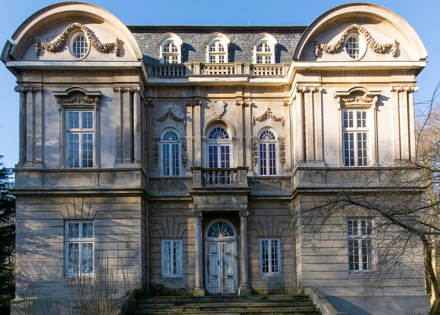 Historic villa façade with symmetrical wooden windows and classical architectural detailing